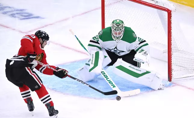 Dallas Stars goalie Jake Oettinger, right, makes a save against Chicago Blackhawks' Roman Kantserov, left, during the second period of an NHL hockey game Saturday, Oct. 17, 2026, in Chicago. (AP Photo/Paul Beaty)