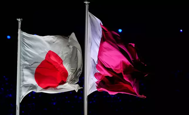 The Qatar and Japanese flag fly during the closing ceremony for the Asian Games in Nagoya, Japan, Sunday, Oct. 4, 2026. (AP Photo/Eugene Hoshiko)