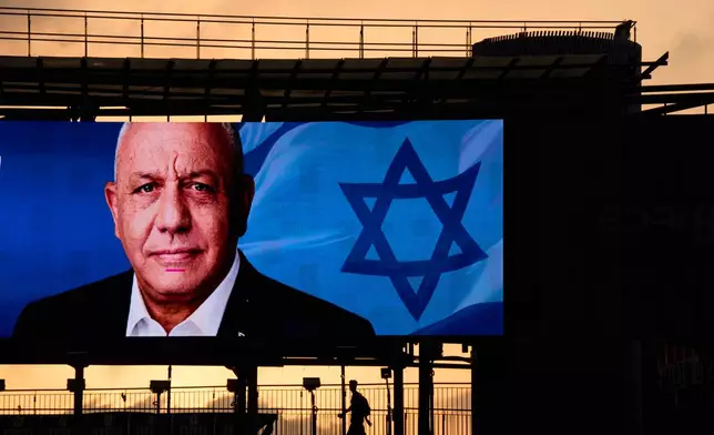 People cross a bridge beneath an election campaign billboard featuring Gadi Eisenkot, leader of Yashar ("Straight") party, ahead of Israel's general election in Ramat Gan, Israel, Sunday, Oct. 25, 2026. (AP Photo/Oded Balilty)