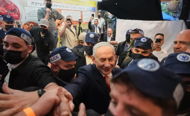 Israeli Prime Minister Benjamin Netanyahu, leader of the Likud party, gestures to supporters as security personnel surround him during a campaign appearance at a market in Tel Aviv, Israel, Thursday, Oct. 22, 2026, ahead of the country's general election. (AP Photo/Ariel Schalit)