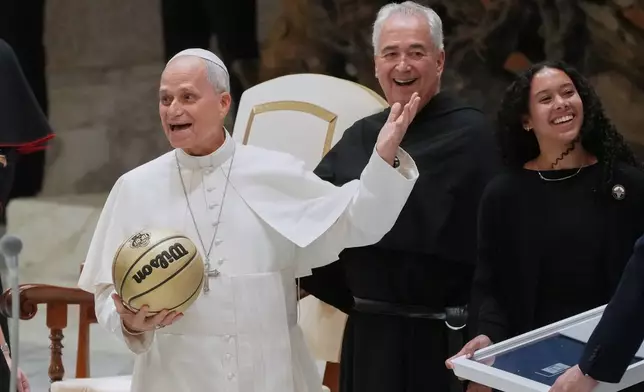 From right Villanova basketball player Jasmine Bascoe along with Villanova University President Peter M. Donohue, present Pope Leo XIV with a basketball in the Paul VI Hall at the Vatican, Saturday, Oct. 31, 2026, during an audience with some 7,000 university representatives ahead of the Eternal City Tip-Off, a men's and women's college basketball doubleheader in Rome on Nov. 1. (AP Photo/Gregorio Borgia)