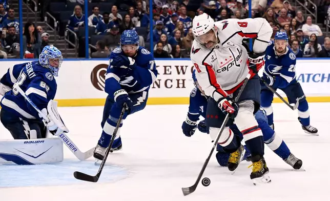 Washington Capitals left wing Alex Ovechkin (8) looks to shoot against Tampa Bay Lightning goaltender Andrei Vasilevskiy (88) and defenseman Victor Hedman (77) during the third period of an NHL hockey game Saturday, Oct. 3, 2026, in Tampa, Fla. (AP Photo/Jason Behnken)
