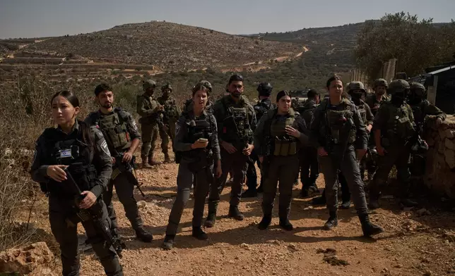 Members of Israeli forces block a road preventing Palestinians from reaching groves to harvest olives in the West Bank town of Turmus Ayya, Wednesday, Oct. 21, 2026. (AP Photo/Leo Correa)
