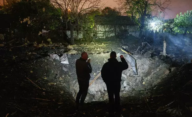 People look at a crater after a Russian missile strike in a residential neighborhood in Kyiv, Ukraine, Wednesday, Oct. 21, 2026. (AP Photo/Evgeniy Maloletka)