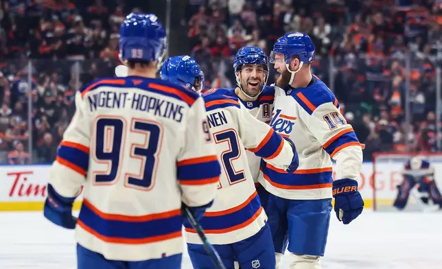 Edmonton Oilers' Evan Bouchard, second right, and Mattias Ekholm, right, celebrate Ekholm's goal against the Calgary Flames during the second period of an NHL hockey game in Edmonton, Alberta, Wednesday, Oct. 28, 2026. (Codie McLachlan/The Canadian Press via AP)