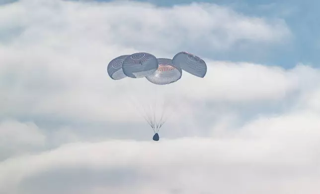 In this photo provided by NASA, the SpaceX Crew Dragon Freedom spacecraft uses parachutes for splashdown in the Pacific Ocean off the coast of California on Thursday, Oct. 8, 2026, returning from the International Space Station. (Keegan Barber/NASA via AP)