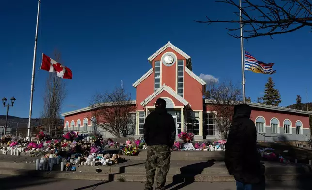 FILE - People pay their respects at a memorial on the steps of the Town Hall, following a vigil the previous day, in Tumbler Ridge, British Columbia, Canada, Feb. 14, 2026. (Christinne Muschi/The Canadian Press via AP, File)
