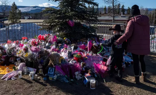 FILE - A mother and son pay their respects at a memorial for the victims of a mass shooting in Tumbler Ridge, British Columbia, Canada, Feb. 14, 2026. (Christinne Muschi/The Canadian Press via AP, File)
