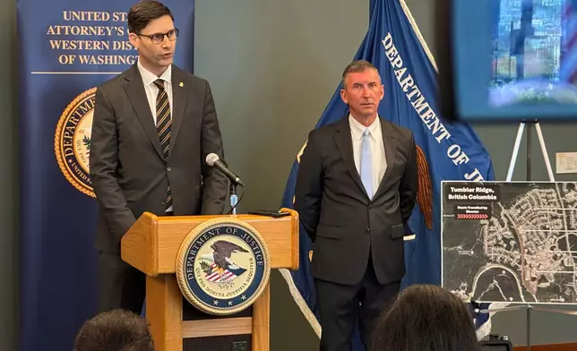 In this photo taken with a smartphone, Mike Herrington, the FBI special agent in charge, speaks to the media while Acting U.S. Attorney Neil Floyd, right, listens, Tuesday, Oct. 6, 2026, in Seattle. (AP Photo/Manuel Valdes)