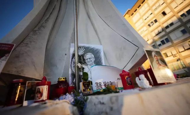 An image of Pope Leo XIV rests at the base of a statue of Pope St. John Paul II at the Agostino Gemelli Polyclinic, where Leo is hospitalized, in Rome, Friday, Oct. 16, 2026. (AP Photo/Andrew Medichini)