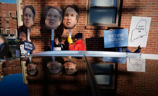Protesters hold photos of U.S. Supreme Court Justice Brett Kavanaugh near a campaign stop by Sen. Susan Collins Wednesday, Oct. 21, 2026, in Lewiston, Maine. (AP Photo/Robert F. Bukaty)