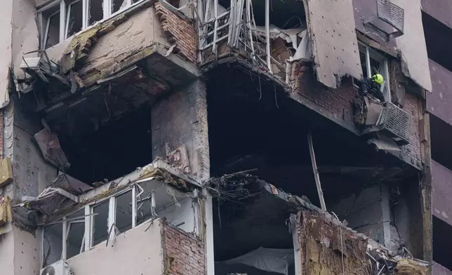 A rescue worker clears the rubble from a multi-story residential building damaged in a Russian drone strike in Kyiv, Ukraine, Wednesday, Oct. 21, 2026. (AP Photo/Evgeniy Maloletka)