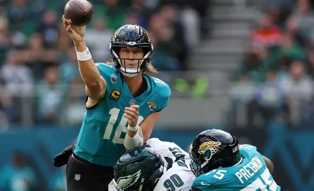 Jacksonville Jaguars quarterback Trevor Lawrence (16) gets a pass away as he is challenged by Philadelphia Eagles defensive tackle Jordan Davis (90) during an NFL football game in London, Sunday, Oct. 11, 2026. (AP Photo/Ian Walton)