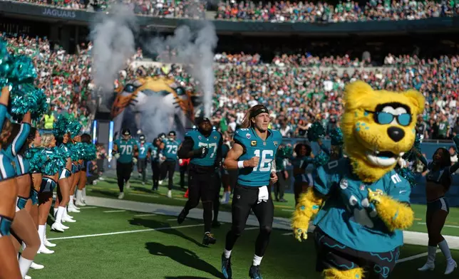 Jacksonville Jaguars quarterback Trevor Lawrence (16) follows Jacksonville Jaguars mascot Jaxson de Ville onto the field before an NFL football game against Philadelphia Eagles in London, Sunday, Oct. 11, 2026. (AP Photo/Ian Walton)