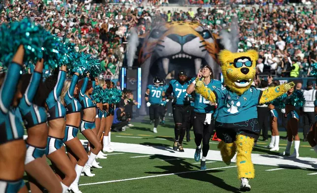Jacksonville Jaguars quarterback Trevor Lawrence (16) follows Jacksonville Jaguars mascot Jaxson de Ville onto the field before an NFL football game against Philadelphia Eagles in London, Sunday, Oct. 11, 2026. (AP Photo/Ian Walton)
