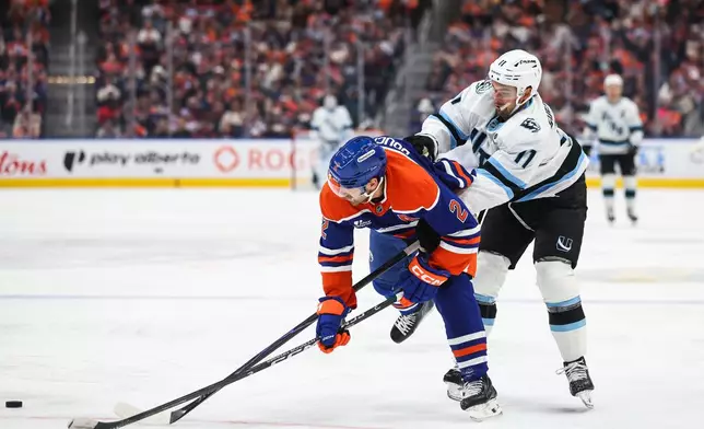 Edmonton Oilers' Evan Bouchard (2) battles against Utah Mammoth's Dylan Guenther (11) during the third period of an NHL hockey game in Edmonton, Alberta, Thursday, Oct. 15, 2026. (Codie McLachlan/The Canadian Press via AP)