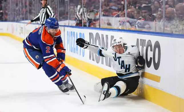 Edmonton Oilers' Evan Bouchard (2) battles against Utah Mammoth's Logan Cooley, right, during the third period of an NHL hockey game in Edmonton, Alberta, Thursday, Oct. 15, 2026. (Codie McLachlan/The Canadian Press via AP)