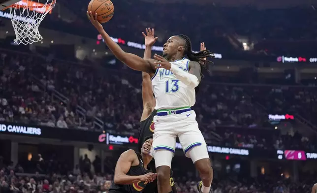 Minnesota Timberwolves guard Ayo Dosunmu (13) shoots in front of Cleveland Cavaliers guard Meleek Thomas, left, and guard Peyton Watson, rear, in the first half of an NBA basketball game, Monday, Oct. 26, 2026, in Cleveland. (AP Photo/Sue Ogrocki)