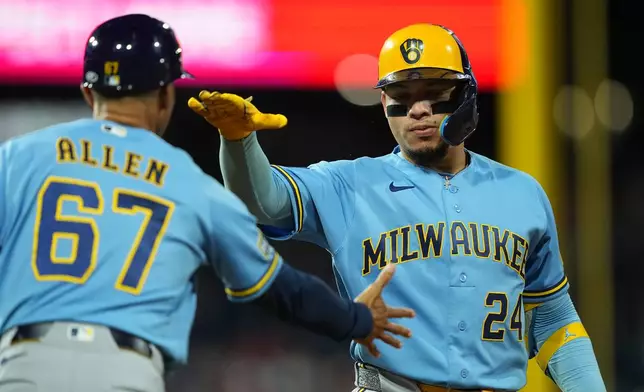 Milwaukee Brewers' William Contreras (24) celebrates his two-run single off of Philadelphia Phillies pitcher Zack Wheeler, with first base coach Spencer Allen during the sixth inning of a baseball game, Tuesday, Sept. 22, 2026, in Philadelphia. (AP Photo/Matt Rourke)