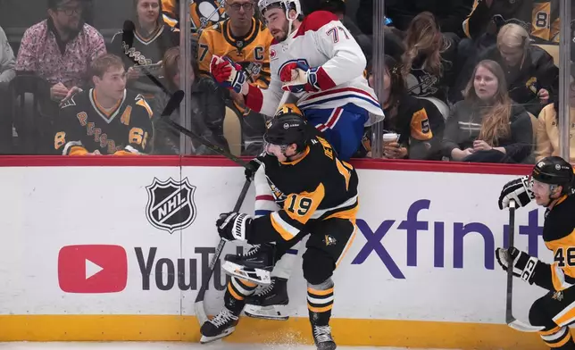 Pittsburgh Penguins' Connor Dewar (19) checks Montreal Canadiens' Jake Evans (71) into the boards during the first period of an NHL hockey game in Pittsburgh, Saturday, Oct. 3, 2026. (AP Photo/Gene J. Puskar)