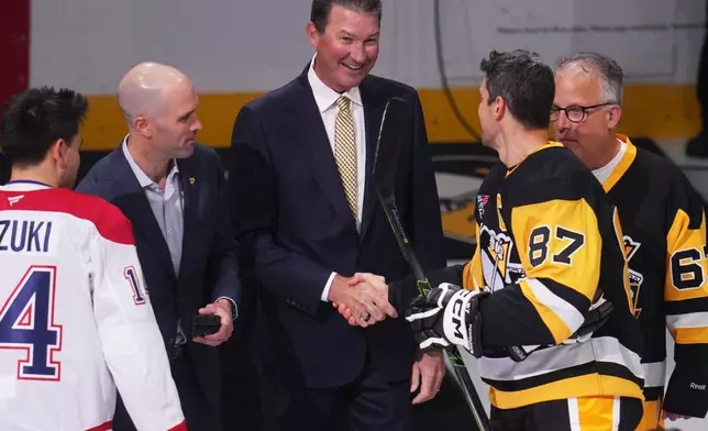 Hockey Hall of Famer and former Pittsburgh Penguins owner and captain Mario Lemieux, center, shakes hands with Penguins captain Sidney Crosby (87) after a ceremonial puck drop with Montreal Canadiens' Nick Suzuki, left, before an NHL hockey game in Pittsburgh, Saturday, Oct. 3, 2026. (AP Photo/Gene J. Puskar)