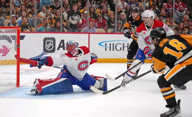Pittsburgh Penguins' Tommy Novak (18) gets a shot past the stick of Montréal Canadiens goaltender Jakub Dobes for a goal during the second period of an NHL hockey game in Pittsburgh, Saturday, Oct. 3, 2026. (AP Photo/Gene J. Puskar)