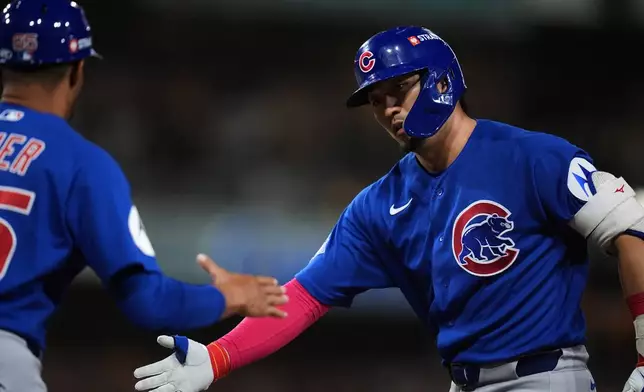 Chicago Cubs Seiya Suzuki is greeted by first base coach Jose Javier, left, after his single against the San Diego Padres in the fourth inning of Game 2 of the National League Wild Card baseball playoff series Wednesday, Sept. 30, 2026, in San Diego. (AP Photo/Gregory Bull)