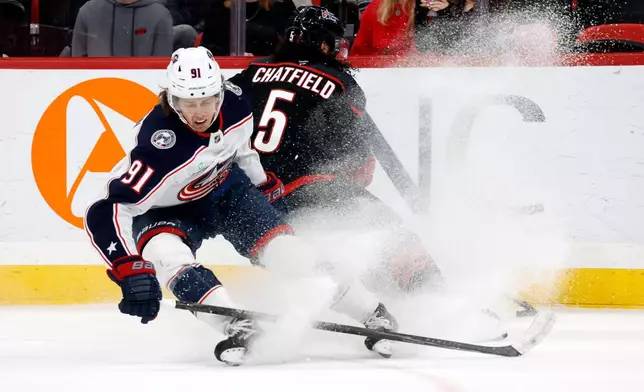 Columbus Blue Jackets' Kent Johnson (91) gets knocked off the puck by Carolina Hurricanes' Jalen Chatfield (5) during the first period of an NHL hockey game in Raleigh, N.C., Thursday, Oct. 29, 2026. (AP Photo/Karl DeBlaker)