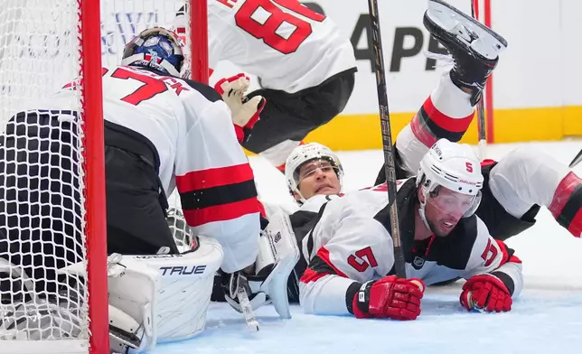 New Jersey Devils goaltender Connor Hellebuyck, left, defenseman Johnathan Kovacevic, center, and defenseman Brenden Dillon, right,, collide while defending their net against the Dallas Stars during the first period of an NHL hockey game Tuesday, Oct. 27, 2026, in Dallas. (AP Photo/Julio Cortez)