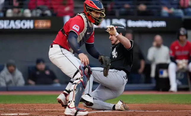 Chicago White Sox's Kyle Teel, right, scores off an RBI-single by baseman Munetaka Murakami ahead of Cleveland Guardians catcher Patrick Bailey during the fourth inning of Game 2 of baseball's American League Division Series, Monday, Oct. 5, 2026, in Cleveland. (AP Photo/Sue Ogrocki)