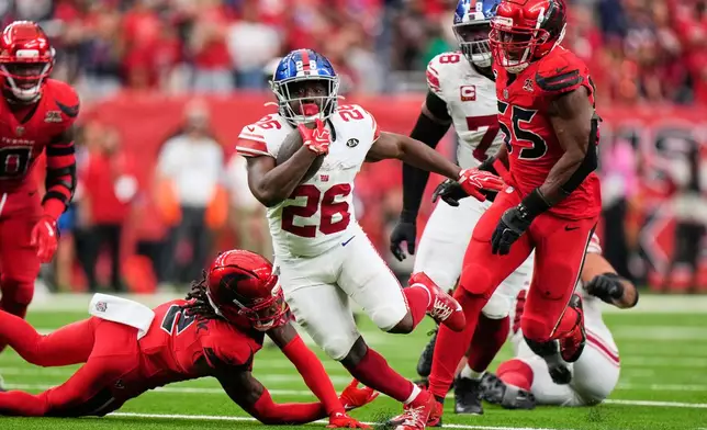 New York Giants running back Devin Singletary (26) breaks away from Houston Texans defenders to score the winning touchdown in overtime of an NFL football game in Houston, Sunday, Oct. 25, 2026. (AP Photo/Gerald Herbert)