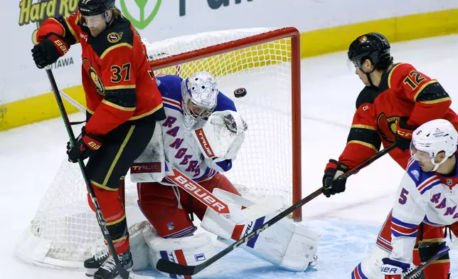 New York Rangers goaltender Dylan Garand, second from left, makes a save as Ottawa Senators' Warren Foegele (37), Senators' Shane Pinto (12) and Rangers' Sean Durzi (5) look on during the first period of an NHL hockey game in Ottawa, Ontario, Saturday, Oct. 24, 2026. (Patrick Doyle/The Canadian Press via AP)