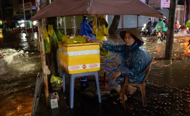 A woman sells food surrounded by floodwaters rain and high tide cause flooding on Pham Huu Lau Street in Ho Chi Minh City, Vietnam, Wednesday, Sept. 30, 2026. (AP Photo/Thanh Hue)