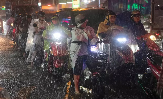 People ride motorbikes through floodwater caused by rain and high tide, on Pham Huu Lau Street in Ho Chi Minh City, Vietnam, Wednesday, Sept. 30, 2026. (AP Photo/Thanh Hue)