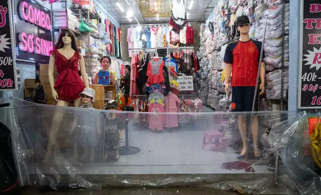 A woman puts up a plastic barrier to keep floodwater out of her shop, as rain and high tide cause flooding on Pham Huu Lau Street in Ho Chi Minh City, Vietnam, Wednesday, Sept. 30, 2026. (AP Photo/Thanh Hue)