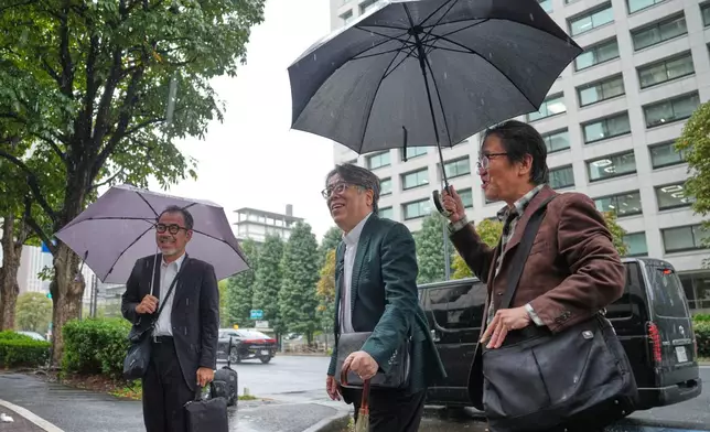 Japanese manga artist Yoshinori Kobayashi, center, who has written books on history and monarchy, arrives at the Tokyo District Court in Tokyo, Monday, Oct. 26, 2026. (AP Photo/Eugene Hoshiko)