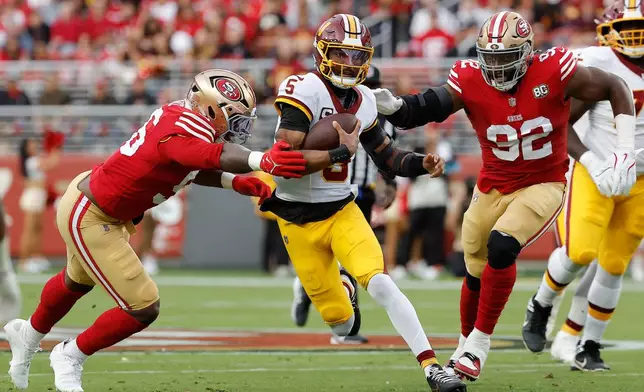 Washington Commanders quarterback Jayden Daniels, middle, runs against San Francisco 49ers defensive end Keion White, left, and defensive tackle Osa Odighizuwa (92) during the first half of an NFL football game in Santa Clara, Calif., Monday, Oct. 19, 2026. (AP Photo/Kelley L. Cox)