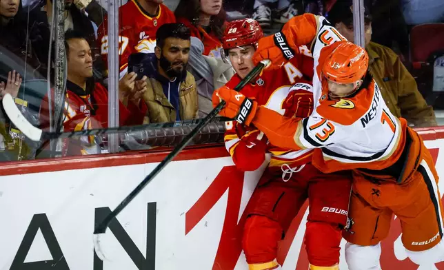 Anaheim Ducks' Nikita Nesterenko, right, checks Calgary Flames' Zach Whitecloud during the second period of an NHL hockey game in Calgary, Alberta, Alberta, Saturday, Oct. 10, 2026. (Jeff McIntosh/The Canadian Press via AP)