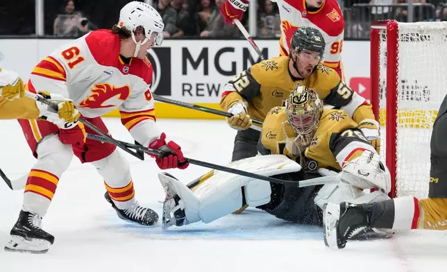 Vegas Golden Knights goaltender Carter Hart (79) stops a shot attempt by Calgary Flames left wing Aydar Suniev (61) during the first period of an NHL hockey game Thursday, Oct. 15, 2026, in Las Vegas. (AP Photo/John Locher)