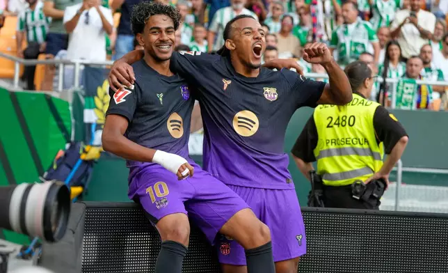 Barcelona's Lamine Yamal, left, celebrates with Barcelona's Jules Kounde after scoring his side's opening goal during the Spanish La Liga soccer match between Real Betis and Barcelona in Seville, Spain, Saturday, Oct. 17, 2026. (AP Photo/Jose Breton)