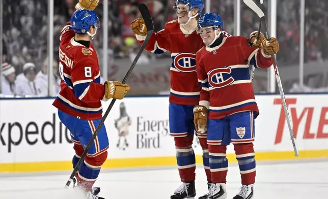 Montreal Canadiens' Kaiden Guhle, center, celebrates after his goal against the Winnipeg Jets with Mike Matheson (8) and Cole Caufield (13) during the second period of the NHL Heritage Classic hockey game in Winnipeg, Manitoba, Sunday, Oct. 25, 2026. (Fred Greenslade/The Canadian Press via AP)