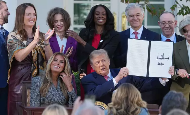 President Donald Trump, with first lady Melania Trump, holds a signed executive order, during an event about women's health, in the Rose Garden of the White House, Monday, Oct. 19, 2026, in Washington. (AP Photo/Mark Schiefelbein)
