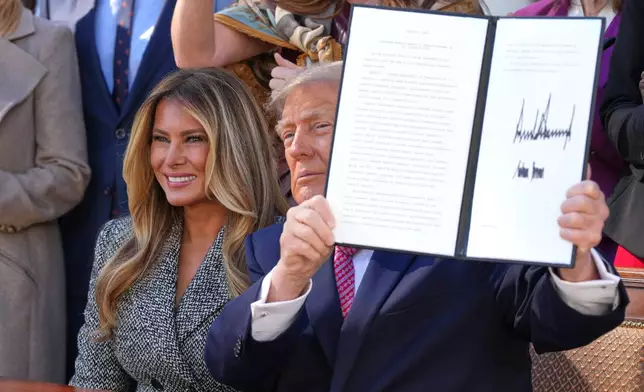 President Donald Trump holds up a signed executive order alongside first lady Melania Trump at an event about women's health, in the Rose Garden of the White House, Monday, Oct. 19, 2026, in Washington. (AP Photo/Alex Brandon)