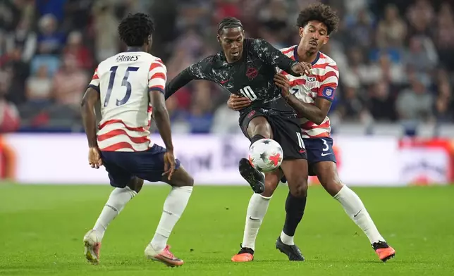 Canada's Jonathan David (10) battles for possession of the ball against United States' Brooklyn Raines (15) and Chris Richards (3) during the first half of an international friendly soccer match Tuesday, Oct. 6, 2026, in St. Paul, Minn. (AP Photo/Abbie Parr)
