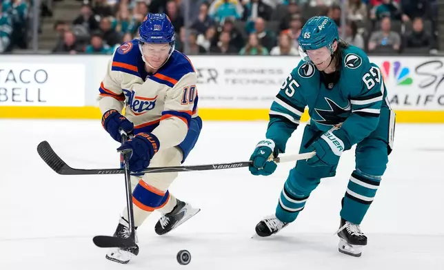 Edmonton Oilers center Trent Frederic (10) battles for the puck with San Jose Sharks defenseman Jacob Trouba (65) during the second period of an NHL hockey game in San Jose, Calif., Saturday, Oct. 10, 2026. (AP Photo/Tony Avelar)