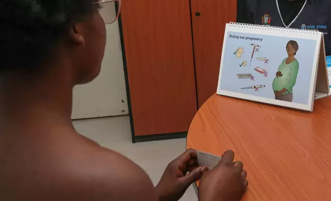A young woman is shown an illustration describing various birth control choices in Lusaka, Zambia, Tuesday, Sept. 8, 2026. (AP Photo/Anita Reed)