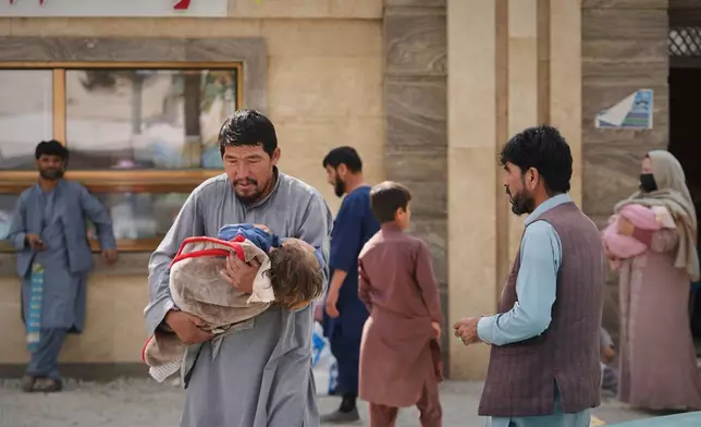 A man carries a child wrapped in a blanket outside Indira Gandhi children's hospital in Kabul, Afghanistan, Monday, Oct. 12, 2026. (AP Photo/Siddiqullah Alizai)