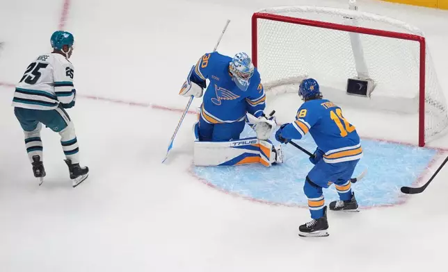 San Jose Sharks' Darnell Nurse (25) scores the game-winning goal past St. Louis Blues goaltender Joel Hofer (30) and Robert Thomas (18) in overtime of an NHL hockey game Thursday, Oct. 8, 2026, in St. Louis. (AP Photo/Jeff Roberson)