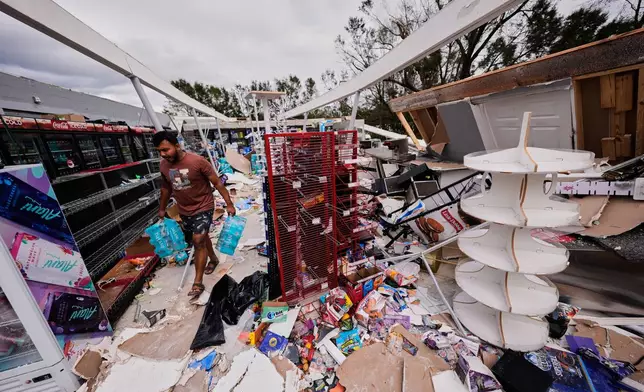 Islam Mahfuz salvages contents of their destroyed mini mart in the aftermath of Hurricane Isaias in Milton, Fla., Saturday, Oct. 10, 2026. (AP Photo/Gerald Herbert)