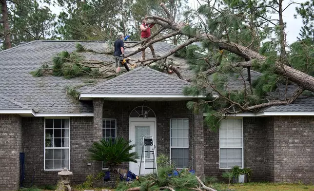 Jeff Lundy cuts up a pine tree that fell on his father-in-law's house during Isaias on Saturday, Oct. 10, 2026, in Milton, Fla. (AP Photo/Octavio Jones)